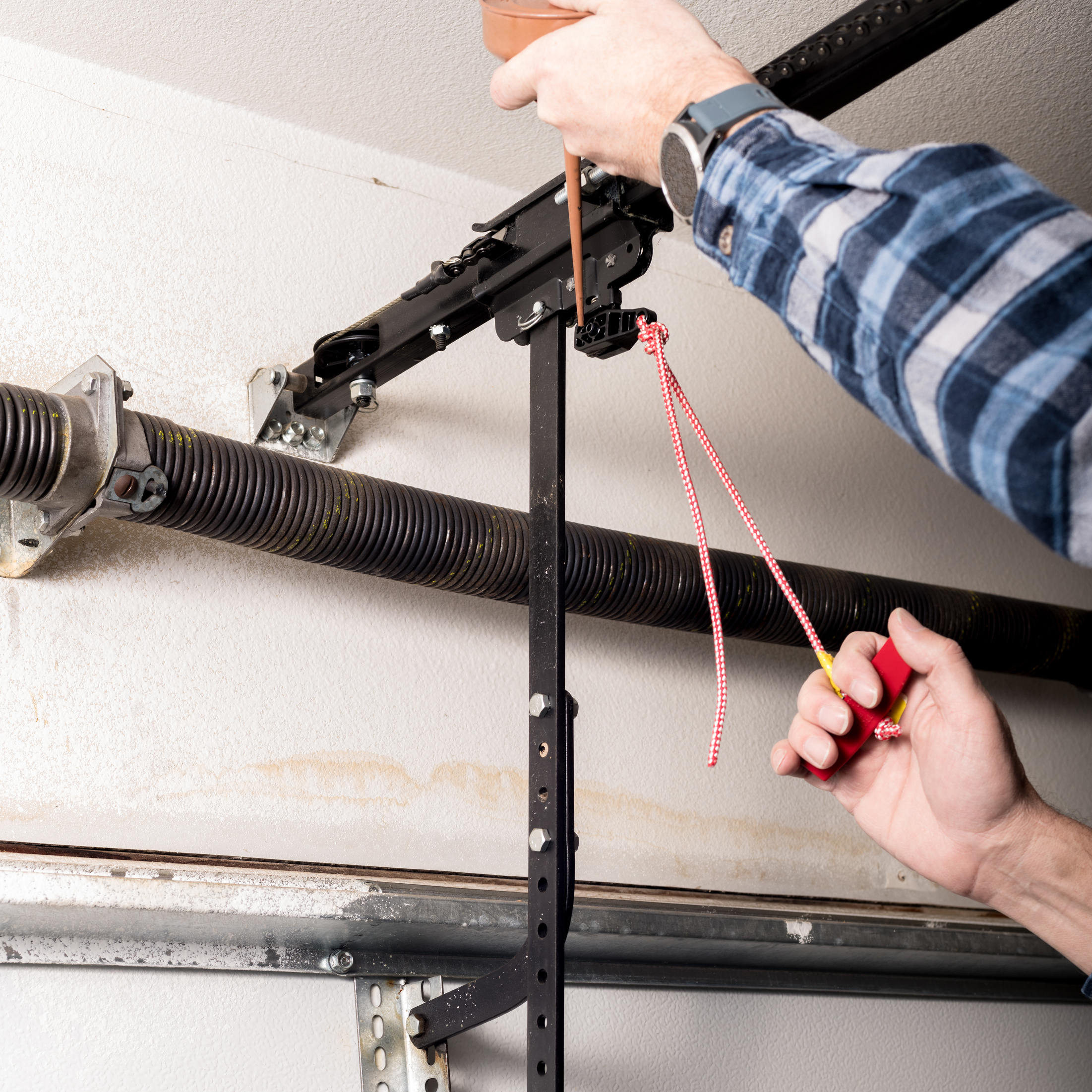 Handyman lubricates a garage door opener release leaver with a can of oil